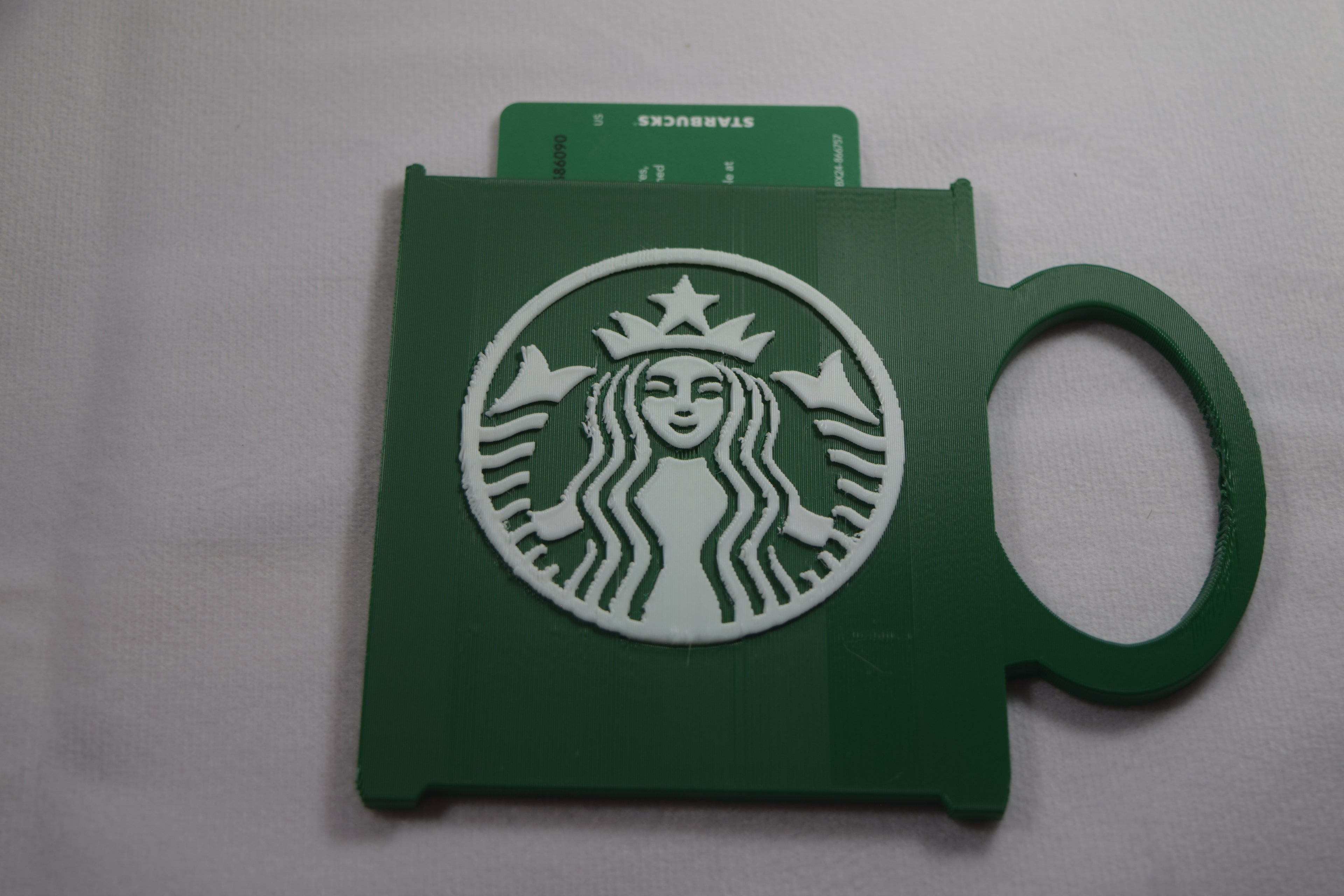 Starbucks mug gift card holder, green 3D-printed plastic with white Starbucks logo and card visible.
